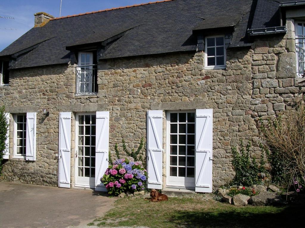 a stone house with white doors and flowers on it at Ty Oceane Erdeven in Erdeven