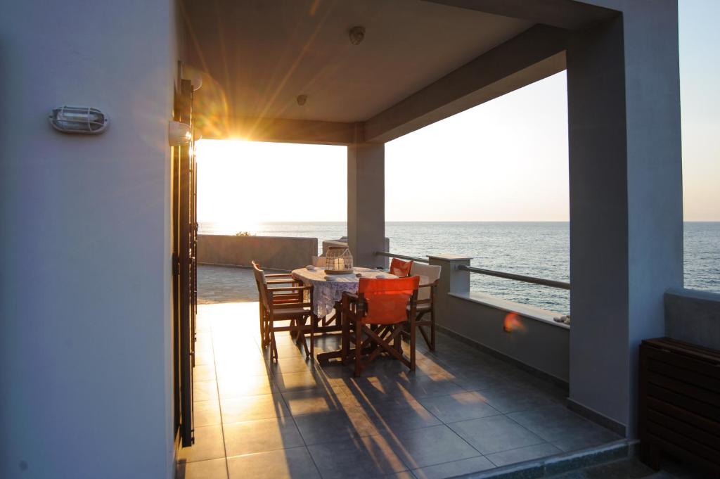 balcón con mesa, sillas y vistas al océano en Albatross House, en Livadáki