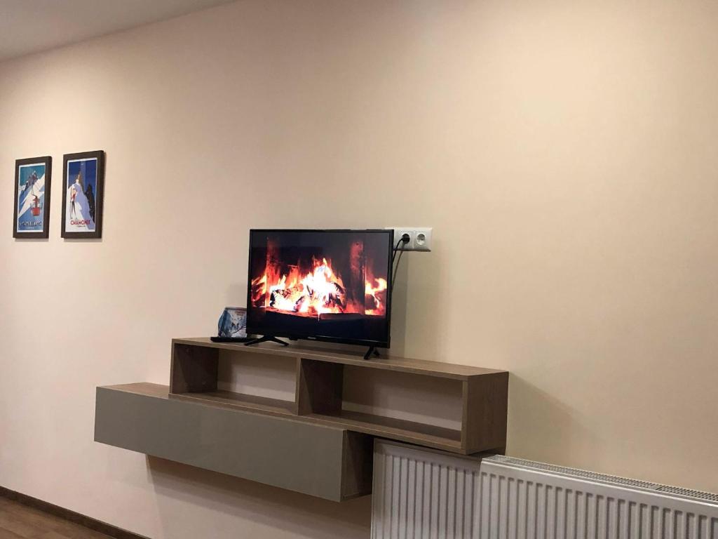 Ein Fernseher steht auf einem Ständer in einem Zimmer mit einem Kamin. in der Unterkunft Ski Heaven in Gudauri