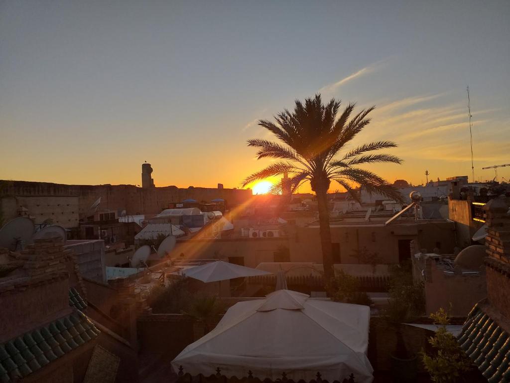 a sunset over a city with a palm tree at Riad Assalam in Marrakech