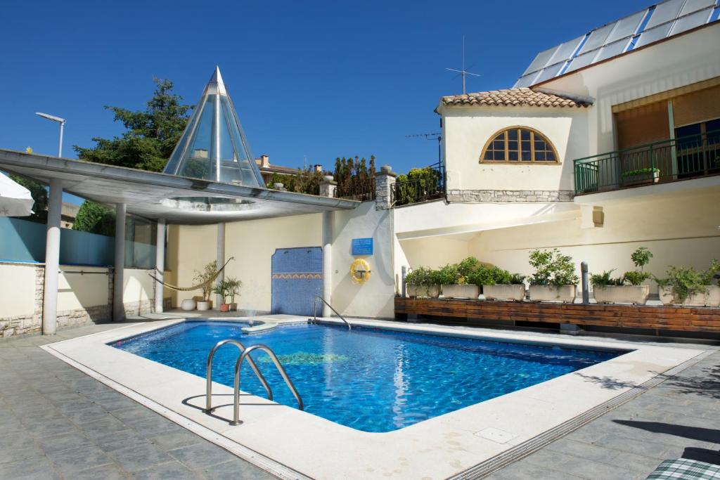 a swimming pool in front of a house at Hotel Rural Jaumet in Torá de Rulbregos