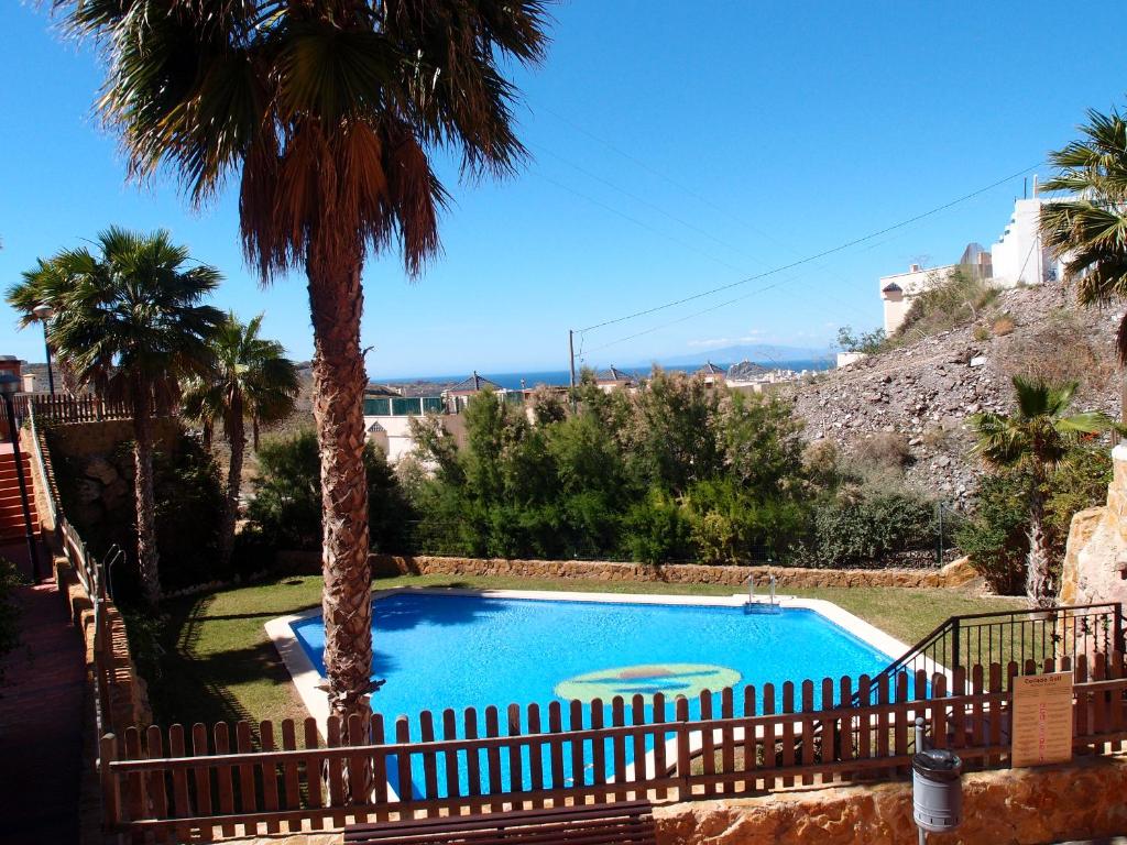 una piscina en un patio con palmeras en Tranquil apartment close to pool, en Águilas