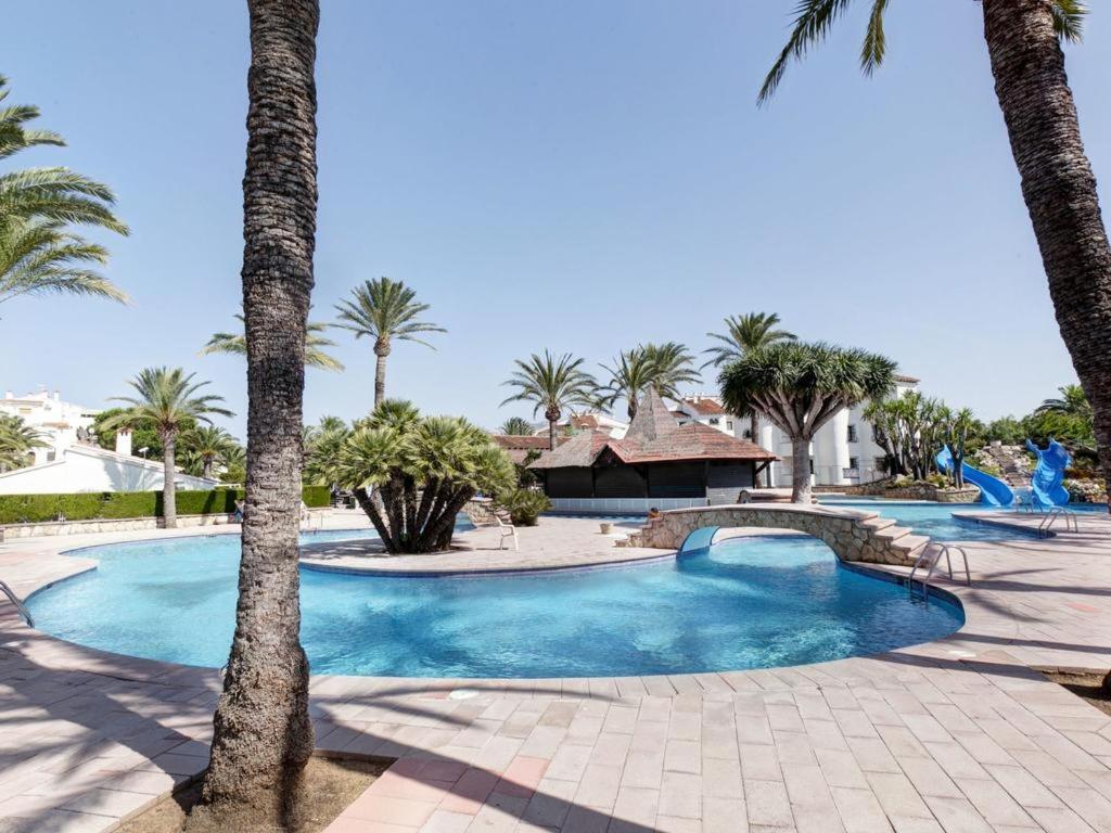 a swimming pool with palm trees in a resort at Apartamento Rey-Piscina in Denia
