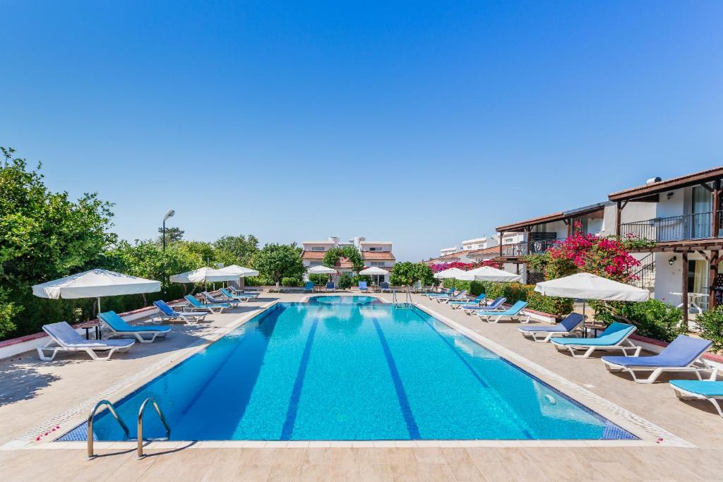 a pool at a hotel with chairs and umbrellas at Citrus Tree Gardens in Kyrenia