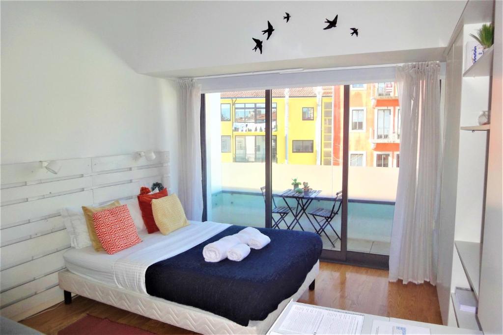 ein Schlafzimmer mit einem Bett und einem Fenster mit Vögeln in der Unterkunft Porto Sunny Terrace Almada in Porto