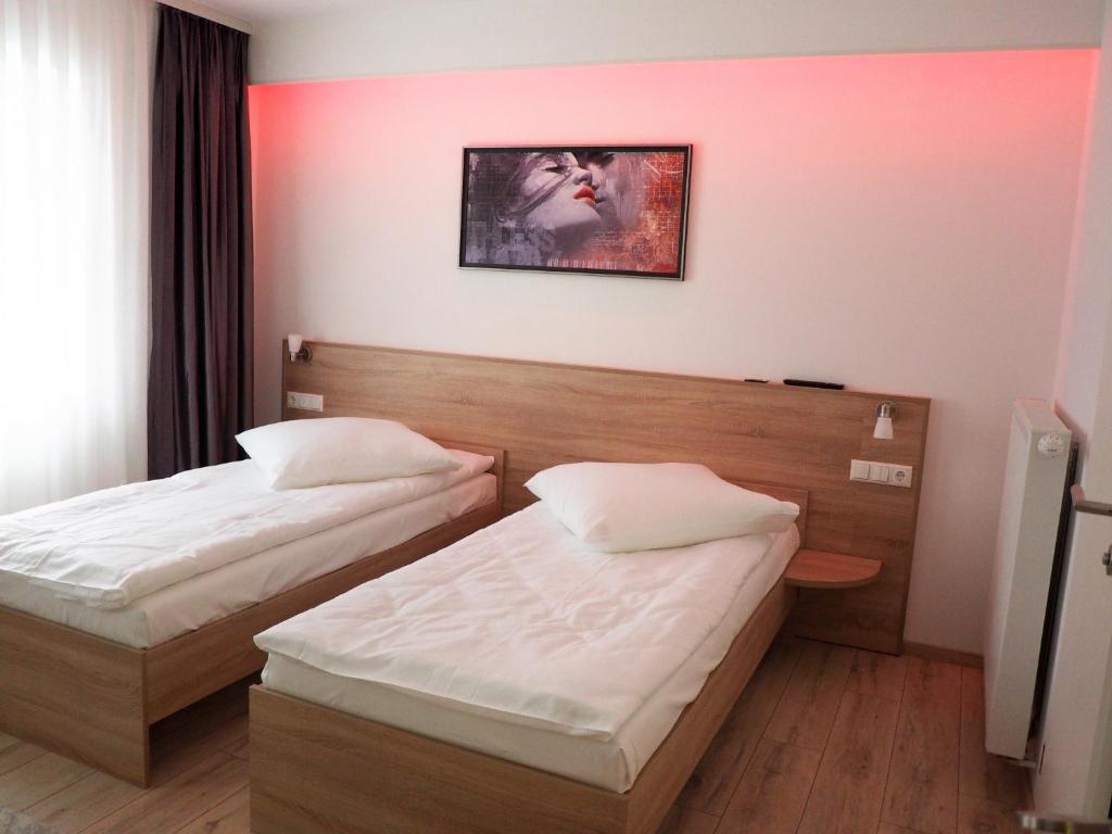 two beds in a hotel room with pink walls at Pension Villa Colosseo im Herzen von Meiningen in Meiningen