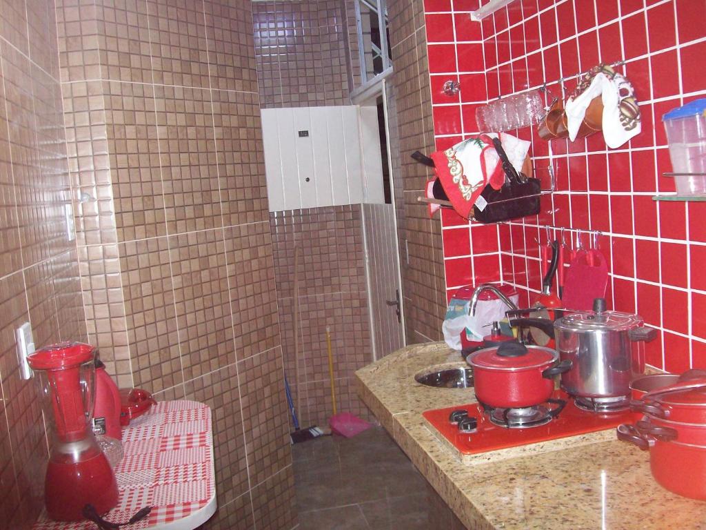 a kitchen with a counter and red tiled walls at KITINETI A 200 M DA PRAIA DO FORTE -PRÉDIO TRÊS RIOS in Cabo Frio