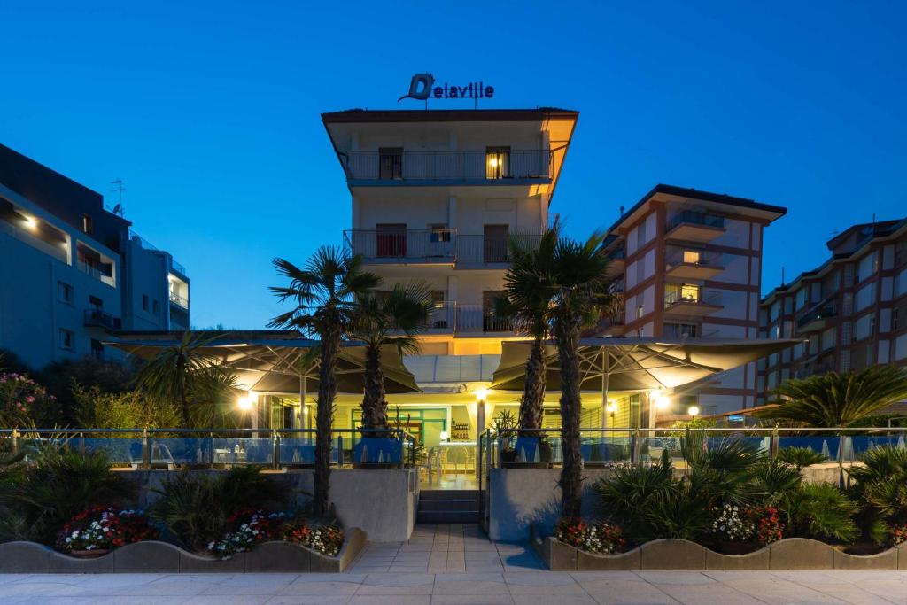 un hotel con palme di fronte a un edificio di Hotel Delaville Frontemare a Lido di Jesolo