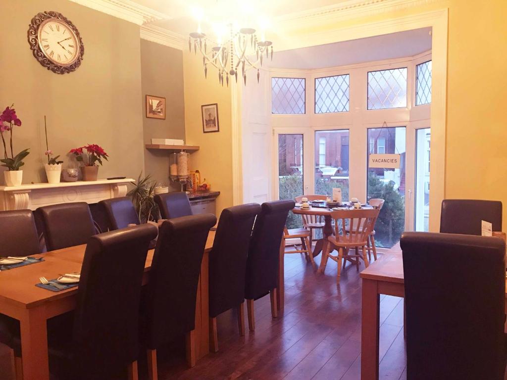 a dining room with a table and chairs and a clock at Esk Vale Guest House in Portsmouth