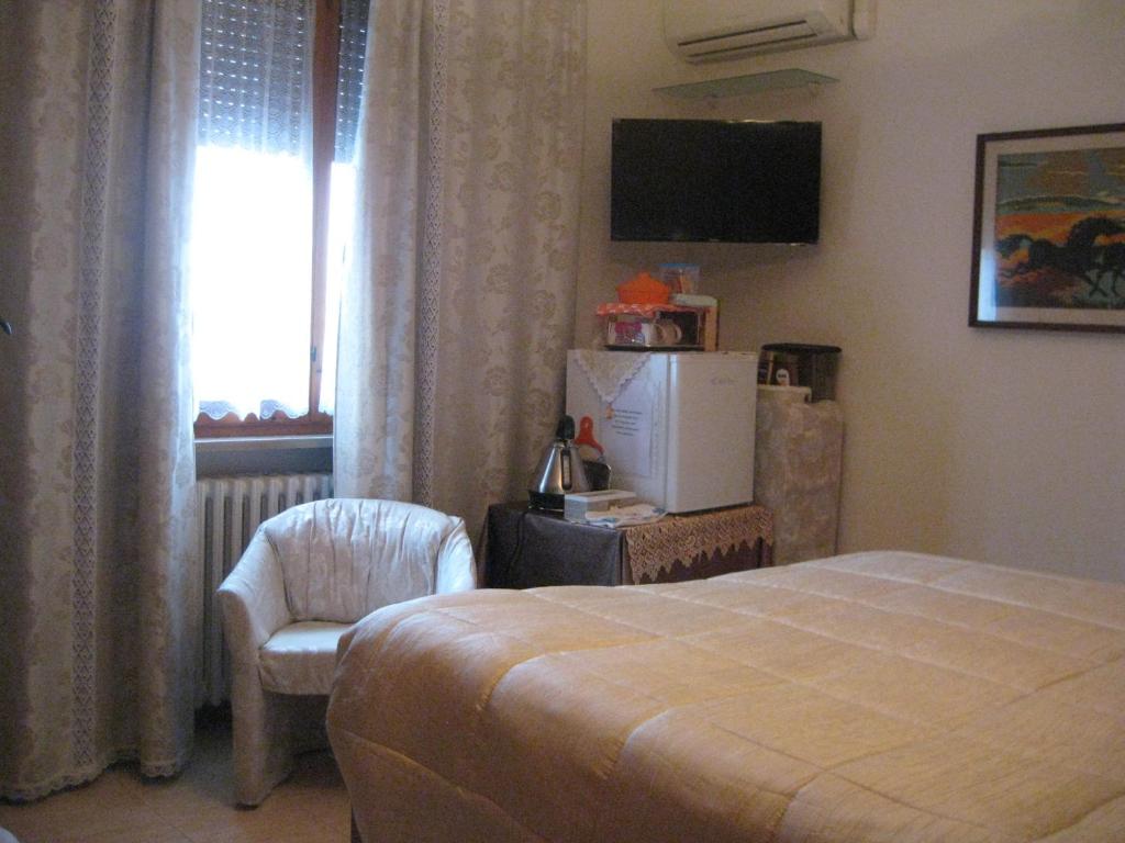 a bedroom with a bed and a chair and a window at Da Lorella in Gabicce Mare