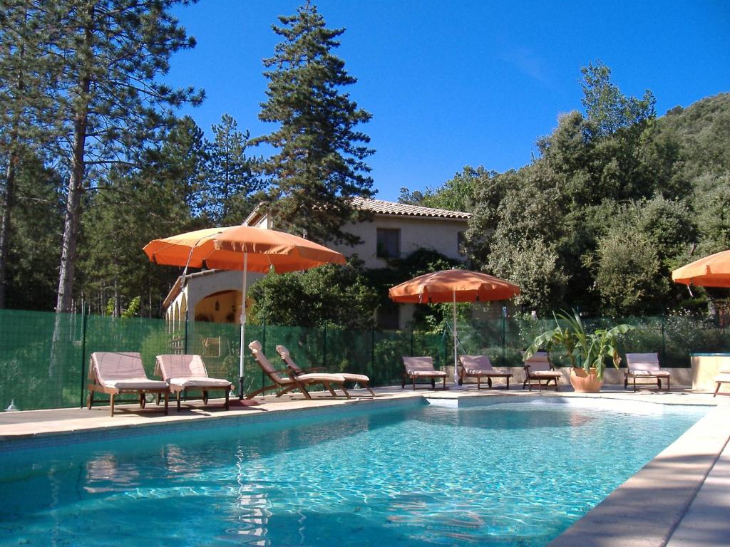 a pool with chairs and umbrellas next to a house at Les Jardins Corbès in Corbés