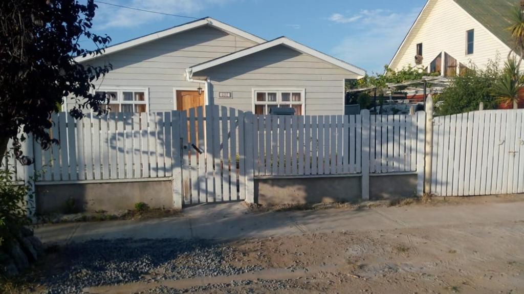 a white fence in front of a white house at Casa en algarrobo in Algarrobo