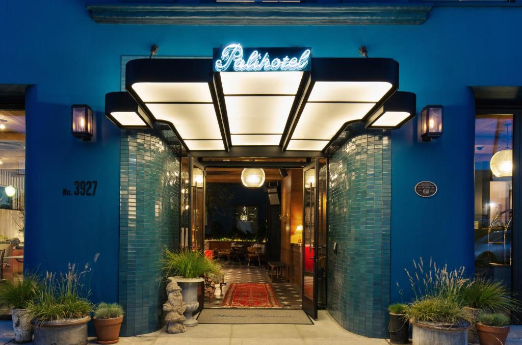a restaurant entrance with a blue wall and a neon sign at Palihotel Culver City in Los Angeles