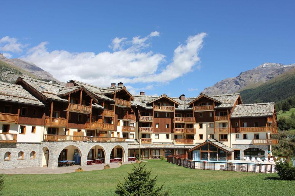 a large resort building with mountains in the background at Les Alpages De Val Cenis by Resid&amp;co in Lanslebourg-Mont-Cenis