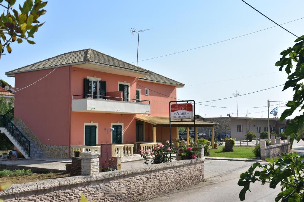 ein rosafarbenes Gebäude mit Balkon auf einer Straße in der Unterkunft Anna Studios in Marathias