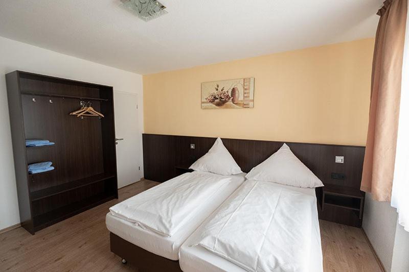 - une chambre avec un grand lit et des draps blancs dans l'établissement Schnitzelhaus und Pension Stadt Rosbach, à Rosbach vor der Höhe
