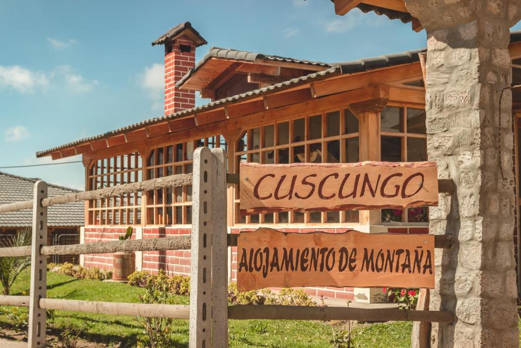 una señal frente a un edificio de madera en Cuscungo Cotopaxi Hostel & Lodge, en Chasqui