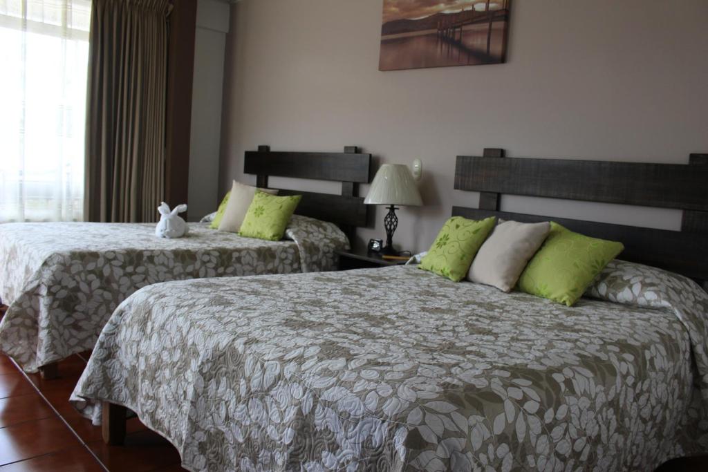 a bedroom with two beds with green pillows at Hotel Arenal By Regina in Fortuna