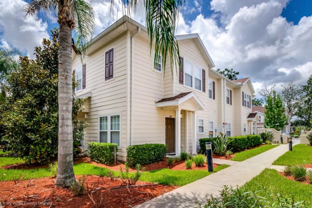 a white house with a palm tree and a sidewalk at Lucaya Village Resort Townhome Unit 14 Townhouse in Orlando