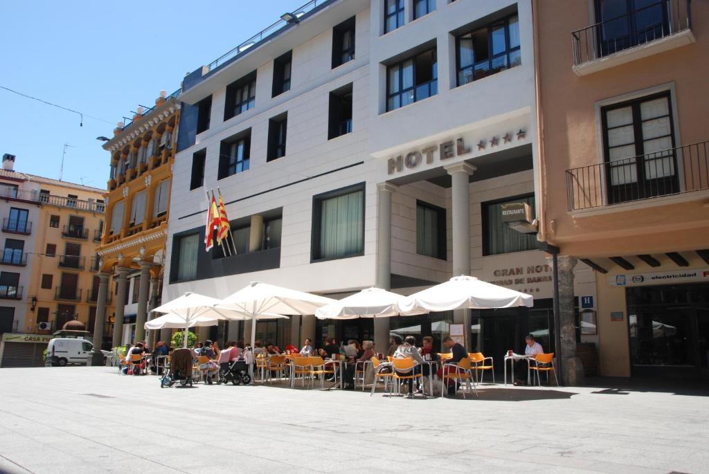 a group of people sitting at tables in front of a hotel at Gran Hotel Ciudad de Barbastro in Barbastro