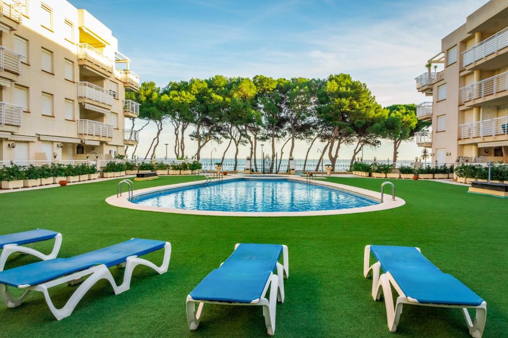 einen Innenhof mit einem Pool und zwei blauen Liegestühlen in der Unterkunft Cala Gonzalez 17 in Alcossebre