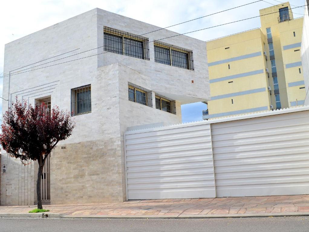 ein Gebäude mit einer weißen Garagentür neben einem Baum in der Unterkunft Vía Lavalle Suites in San Luis