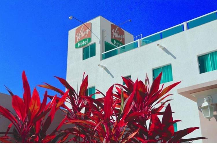 Village Hotel Belém : مبنى أمامه نباتات حمراء