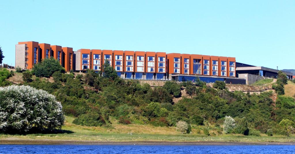 a building on top of a hill next to a body of water at Enjoy Chiloé in Castro