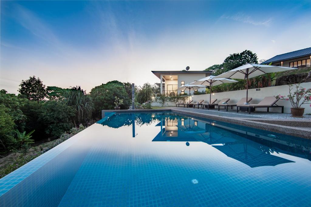 uma piscina com água azul em frente a uma casa em Ranis Lodge em Kampung Padang Masirat