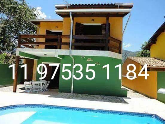 a house with a sign in front of a swimming pool at Casa de férias in Caraguatatuba