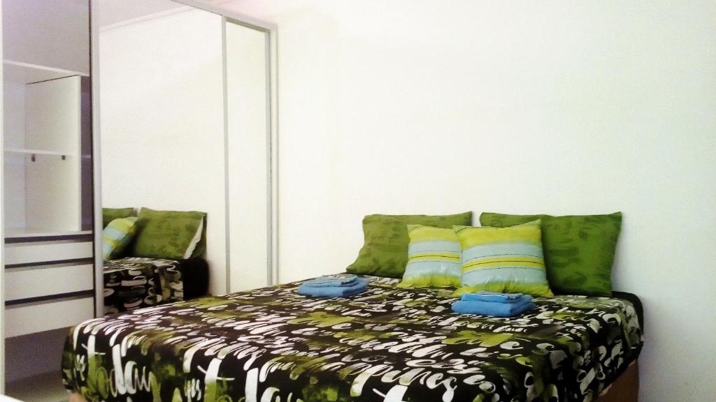 1 dormitorio con cama con almohadas verdes y espejo en Isla Verde en Rosario
