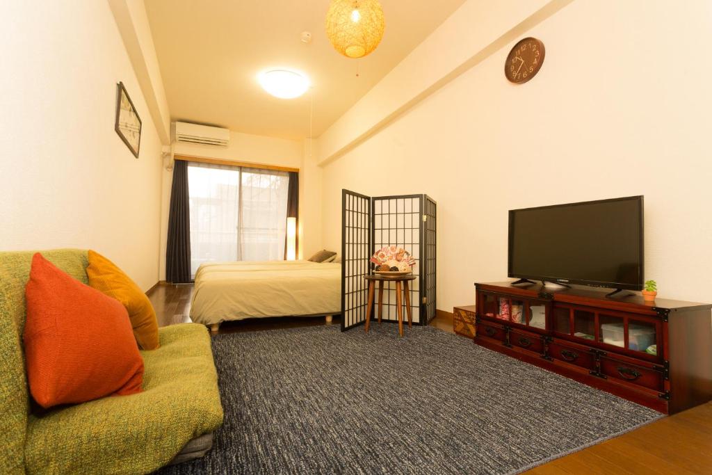 een woonkamer met een televisie en een bed bij Tipy records room in Odawara