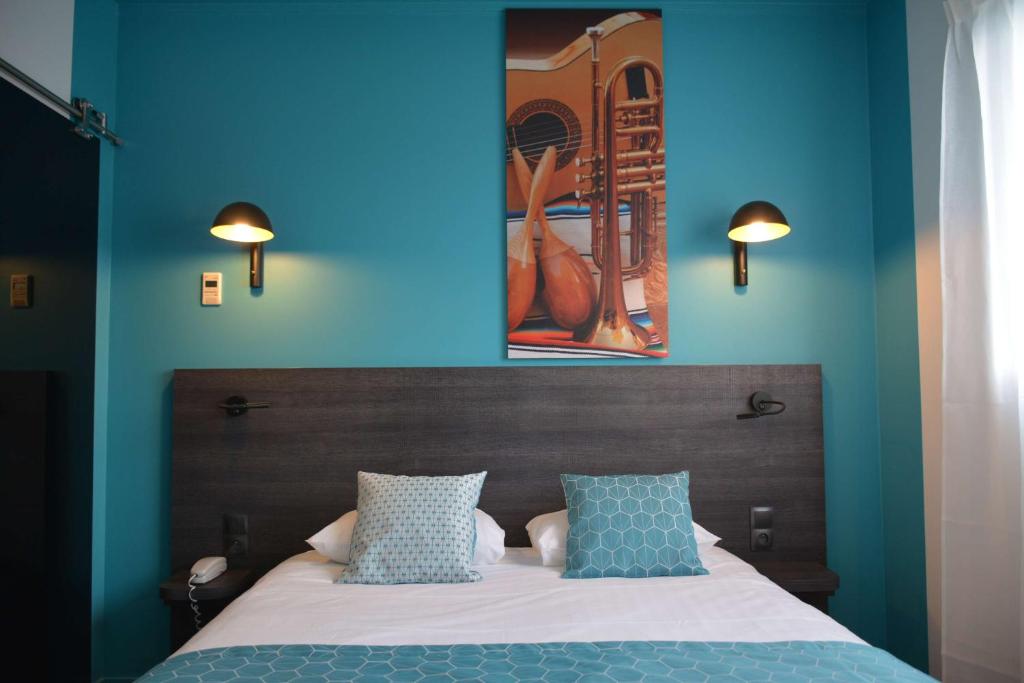 Un dormitorio con una pared azul y una cama con almohadas en Best Western Hotel Atlantys Zenith Nantes, en Saint-Herblain