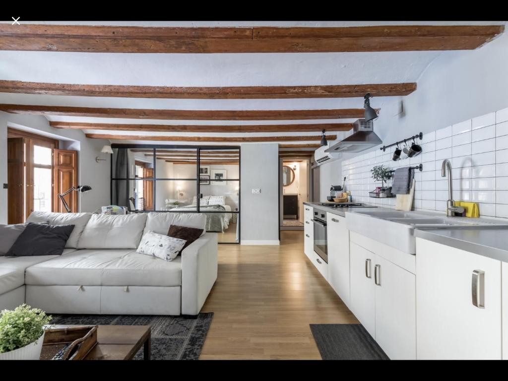 uma sala de estar com um sofá branco e uma cozinha em WeRentVLC - Encantador Loft Casco Antiguo em Valência