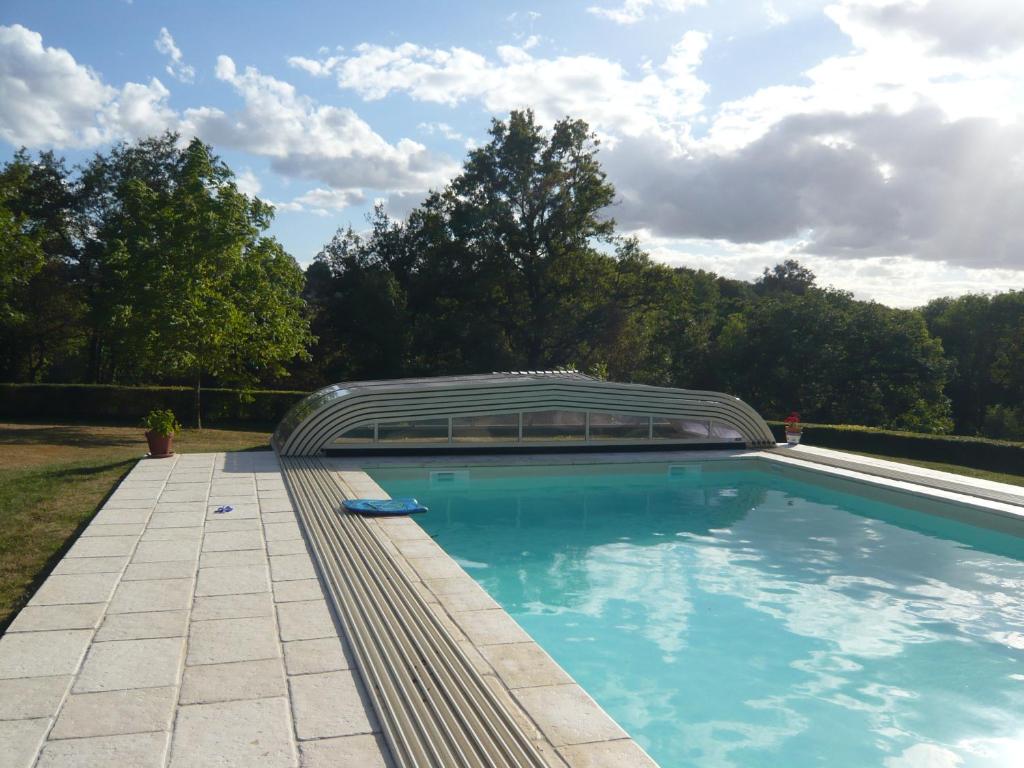 una piscina con una estructura abovedada en un patio en Le Moulin du Cluzeau, en Thollet