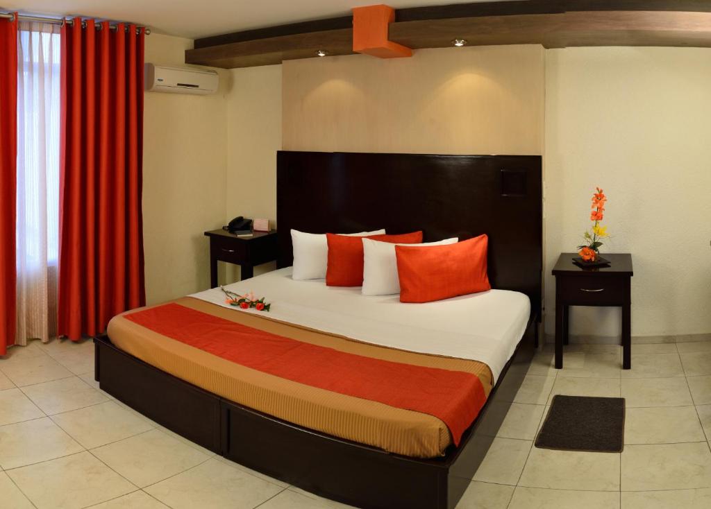 1 dormitorio con 1 cama grande con almohadas de color naranja en Hotel Elizabeth Ciudad Deportiva en Aguascalientes