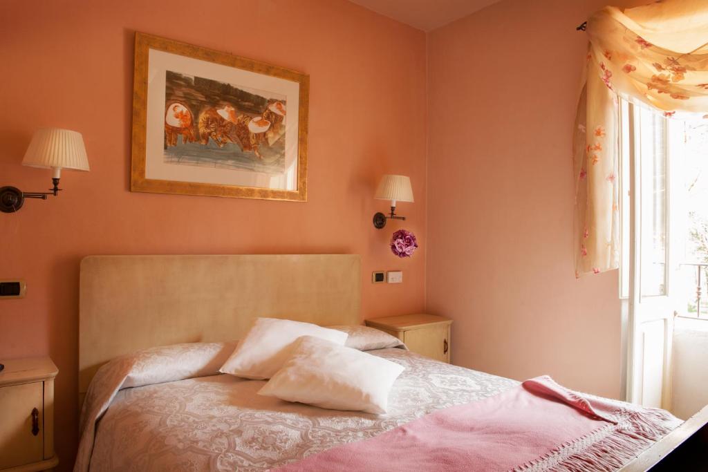 a bedroom with a bed with pink walls and a window at Antico Furlo in Acqualagna
