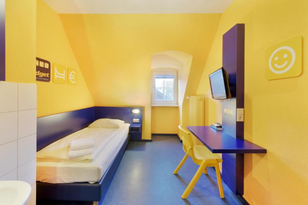 Habitación con cama, escritorio y TV. en Bed'nBudget Expo-Hostel Rooms, en Hannover