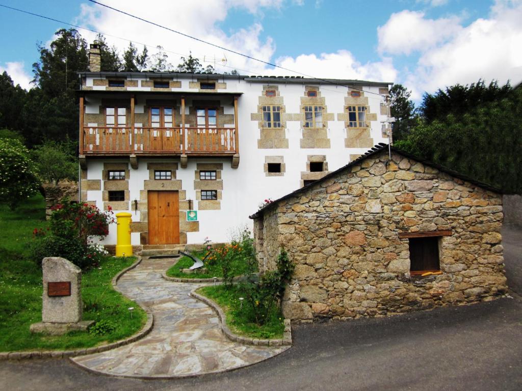 un gran edificio blanco con un balcón en la parte superior. en Casa Os Carballás, en Merille