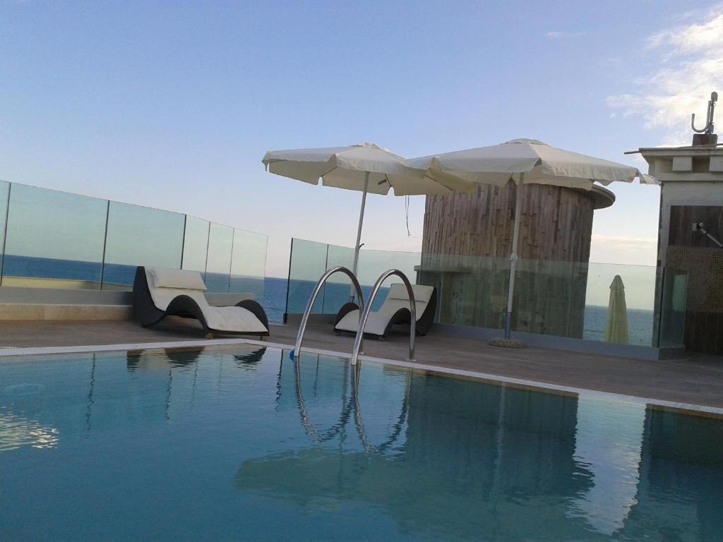 una piscina con sillas y sombrilla en Hotel L'Approdo, en Anzio