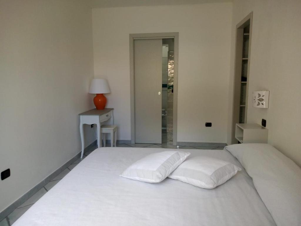 ein weißes Schlafzimmer mit einem weißen Bett und zwei Kissen in der Unterkunft Hotel Alador in Budoni