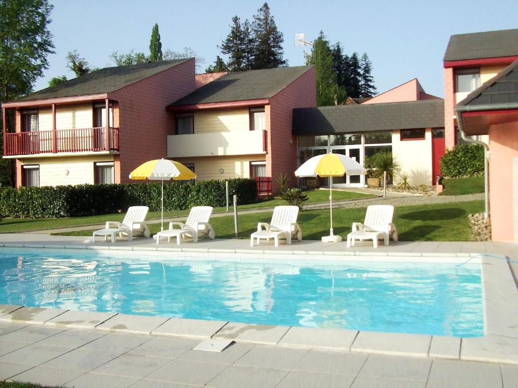 a pool with chairs and umbrellas in front of a house at Les Pavillons du Rooy in Salies-de-Béarn