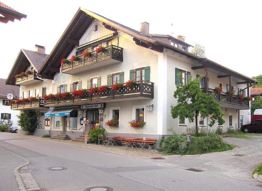 ein großes weißes Gebäude mit Blumenkästen und Balkonen in der Unterkunft Bayersoier Hof in Bayersoien