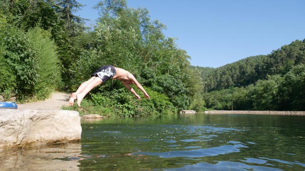 Un homme sautant dans une masse d'eau dans l'établissement Camping des Drouilhèdes, à Peyremale
