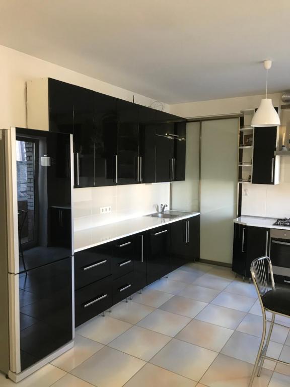 cocina con armarios negros y encimera blanca en Naukova Street Appartamento, en Leópolis