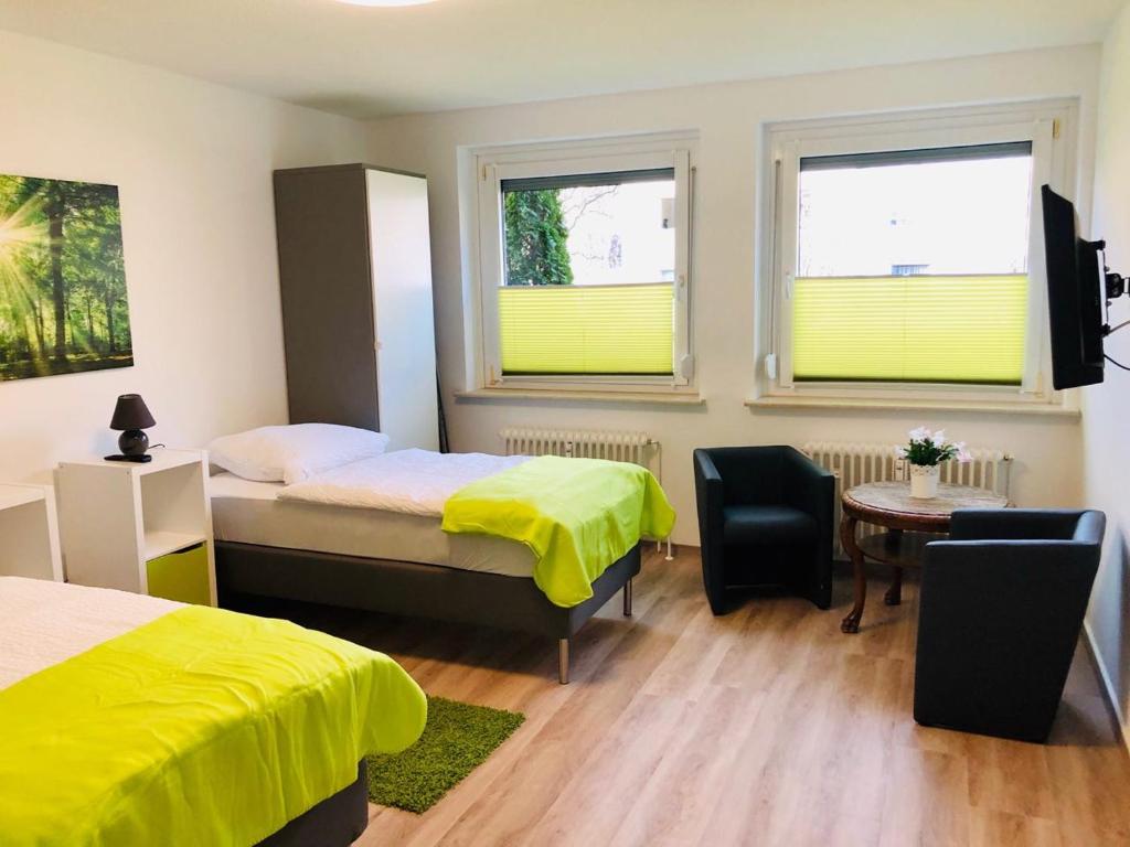 1 dormitorio con 2 camas, mesa y 2 ventanas en Zimmervermietung38 - Wild 1, en Salzgitter