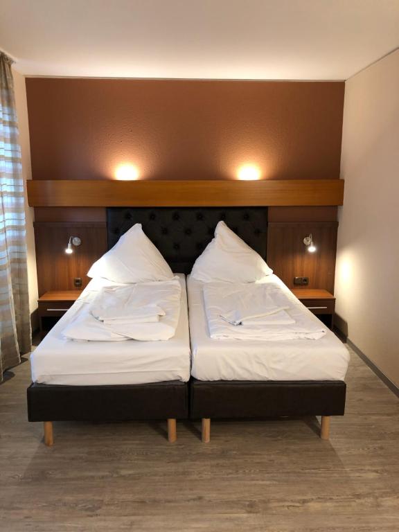 a bed in a room with two pillows on it at Hotel Poseidon in Bayreuth