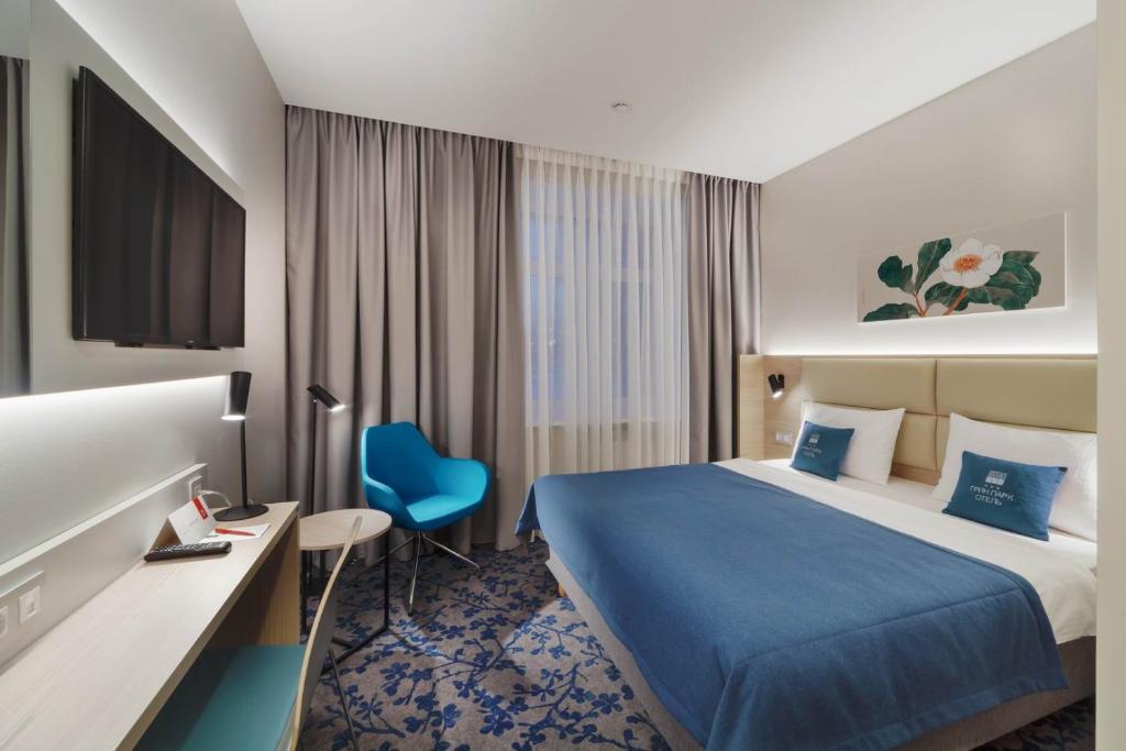 a hotel room with a blue bed and a blue chair at Green Park Hotel in Yekaterinburg