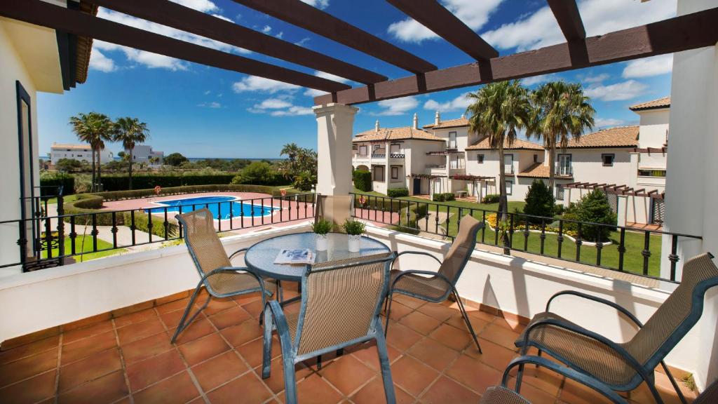 a balcony with a table and chairs and a swimming pool at Leo San Bruno in Isla Canela