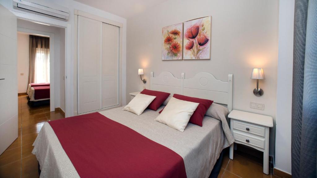 a bedroom with a large bed with red and white pillows at Leo San Bruno in Isla Canela
